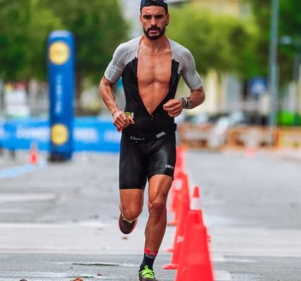 Focused male athlete running a marathon in an urban setting, showcasing endurance and determination.