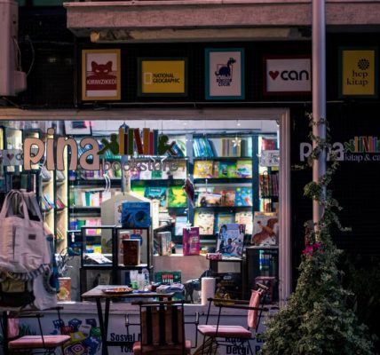 Charming nighttime bookstore and cafe scene, inviting ambiance with outdoor seating and books on display.
