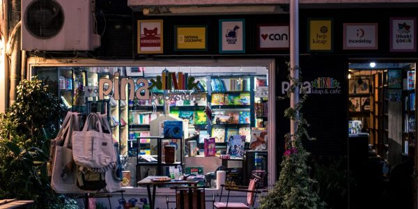 Charming nighttime bookstore and cafe scene, inviting ambiance with outdoor seating and books on display.